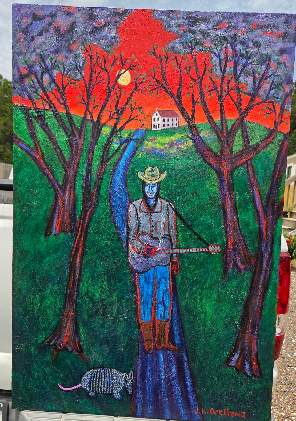 Last Concert, Townes Van Zandt: Townes Van Zandt in a cowboy hat with a red guitar under a red sunset sky. Original acrylic painting by James Orellana.